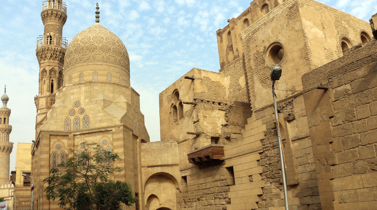 Amir Khayrbak Funerary Complex in Cairo, featuring intricate Islamic architecture with a domed mausoleum, decorative stone carvings, and a historic minaret.