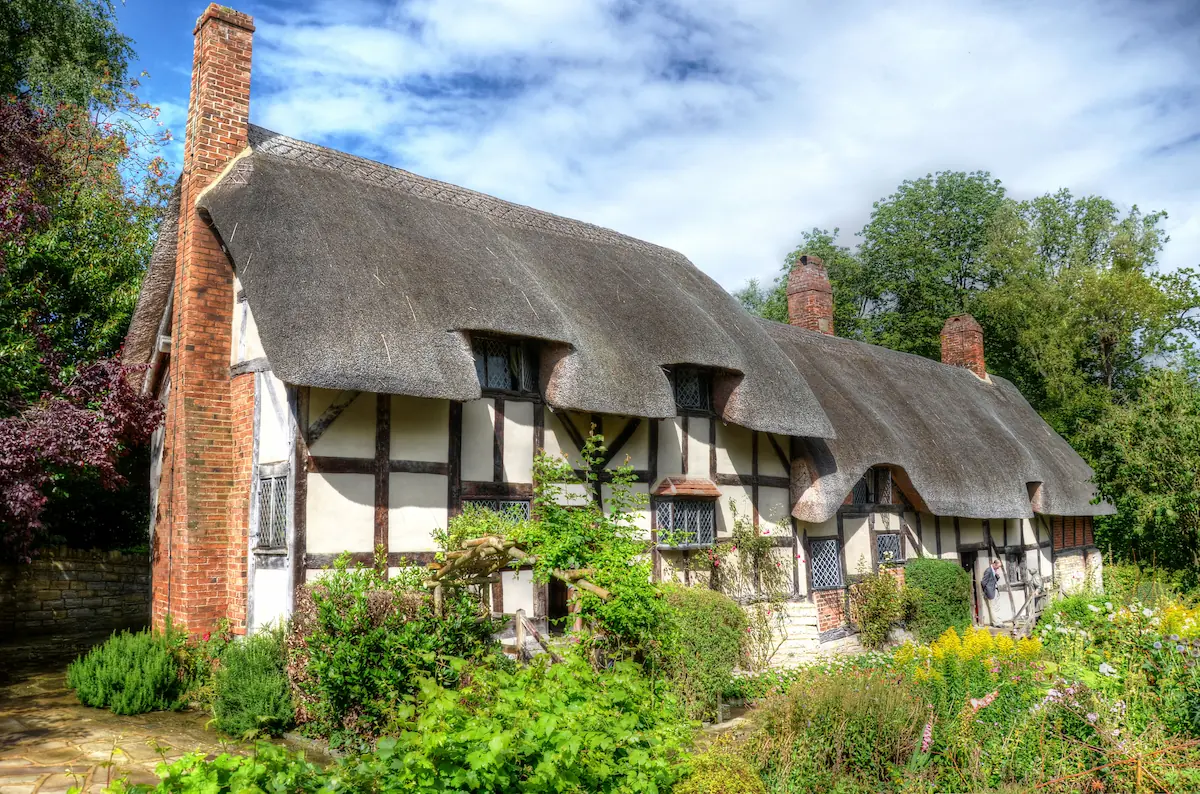 Anne Hathaway's Cottage, a traditional Tudor-style farmhouse with visible timber framing and multiple chimneys.