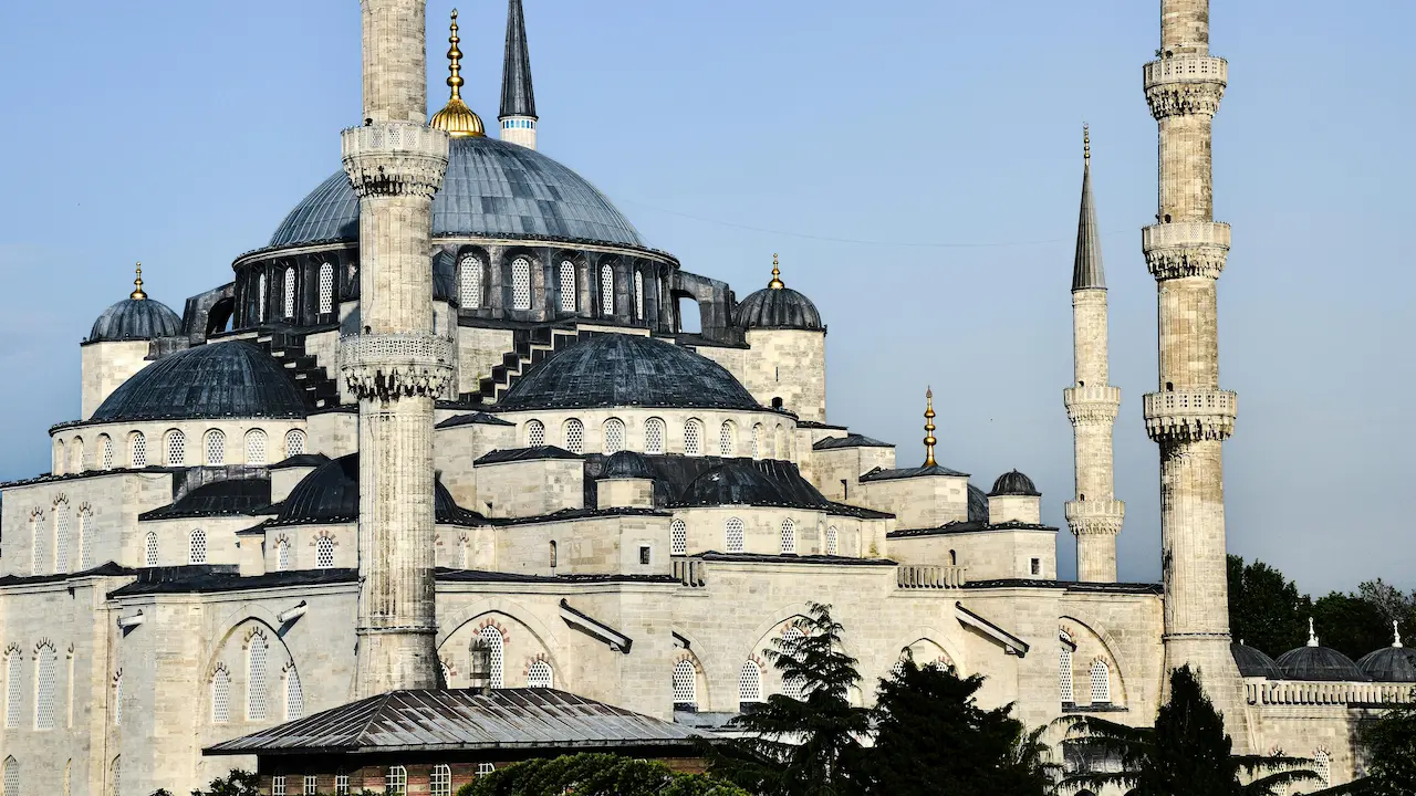 Exterior view of the Blue Mosque (Sultan Ahmed Cami) in Istanbul, Türkiye, showcasing its majestic domes and minarets.