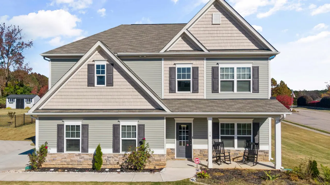 A fully completed house with a well-manicured lawn and clear blue skies.