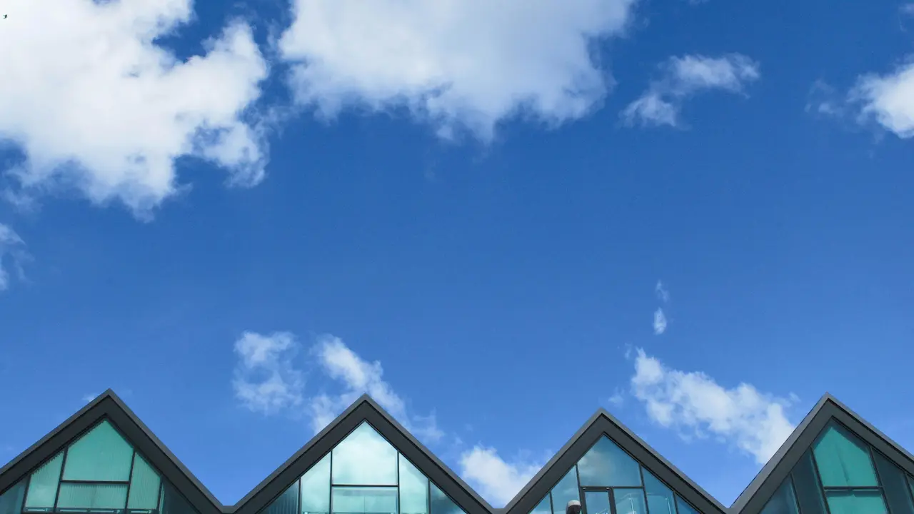 A contemporary house with a grey wood and glass design, featuring a sleek hip roof and expansive windows.