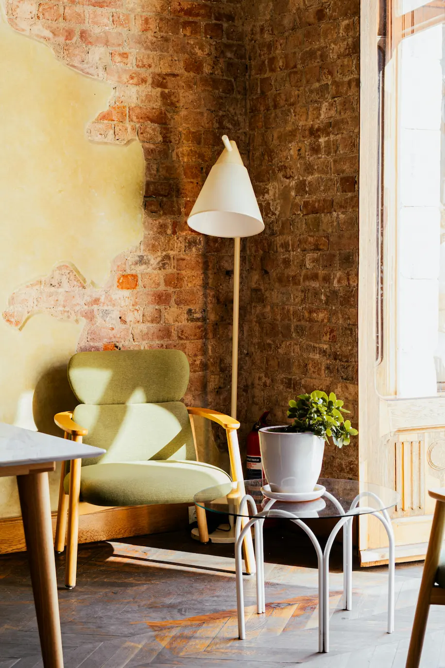 Cozy rustic interior with a green armchair and a charming rustic wall, blending modern and classic design.