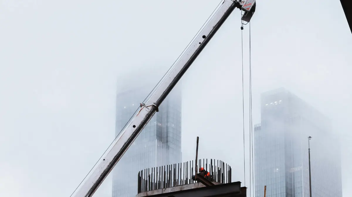 A large crane operating at a modern construction site, lifting materials for building development.