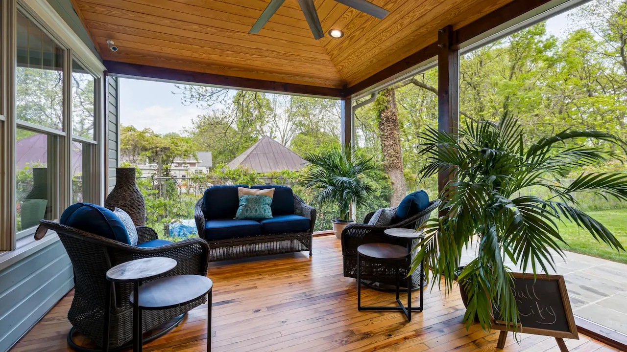 Enclosed patio in a house with comfortable seating and large windows.