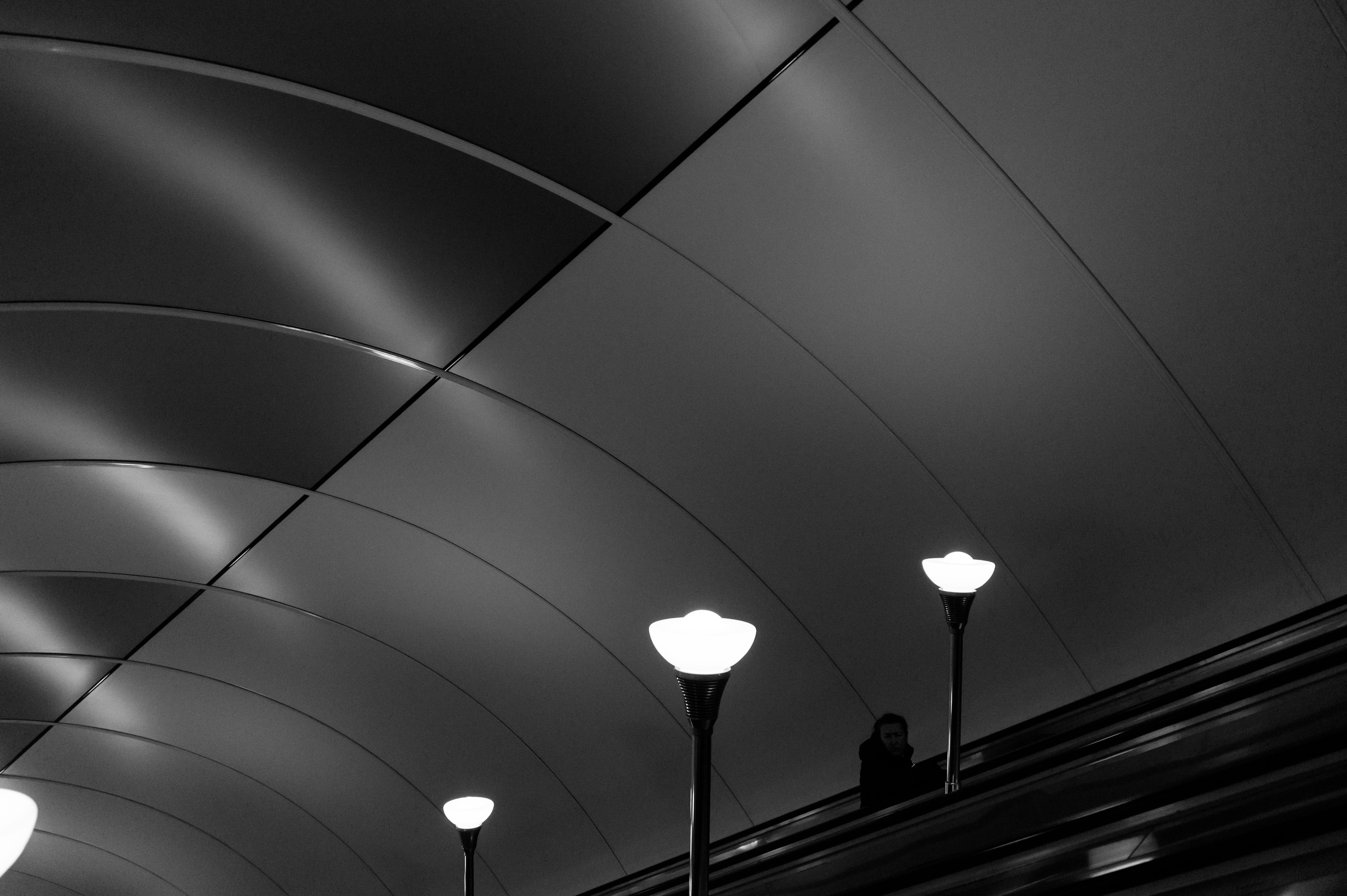 A bright lamps near escalator in dark metal subway.