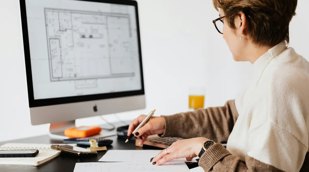 a female architect working on her computer with a blueprint, focused on designing and planning