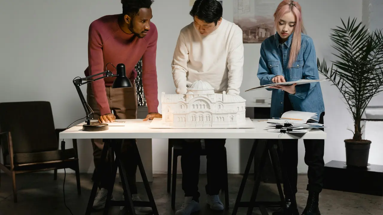 a picture of two men and one woman collaborating on an architecture project, reflecting gender roles in the field