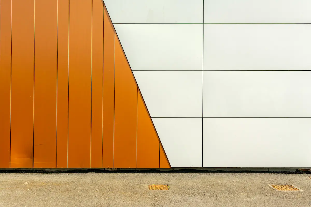A green industrial facade with a modern panel steel door as a focal point.
