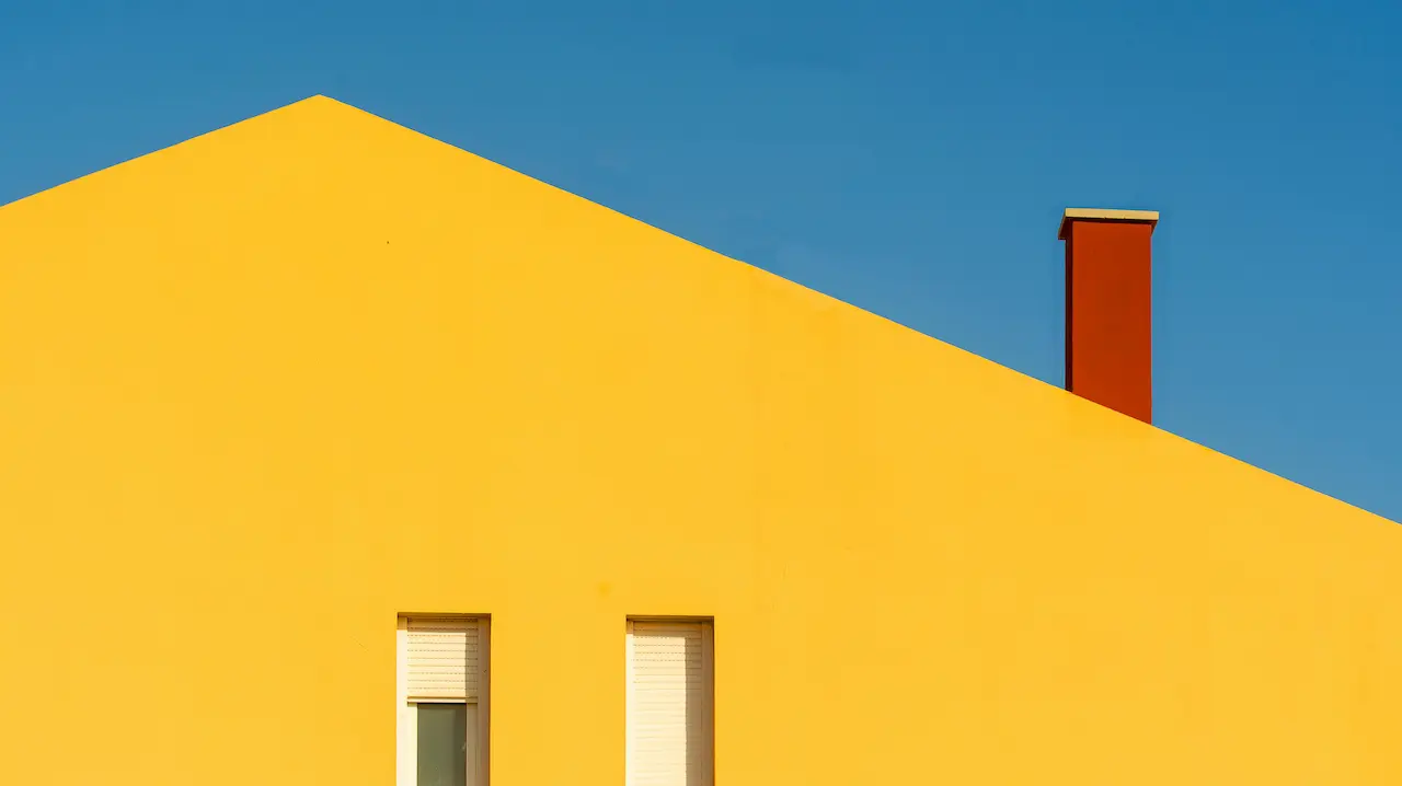 House roof with yellow walls and a red chimney, creating a vibrant exterior design.