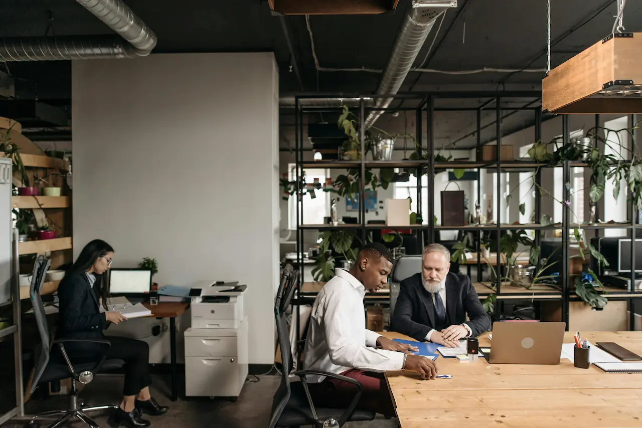 an industrial modern office with exposed brick walls, metal fixtures, sleek minimalist furniture, and employees working