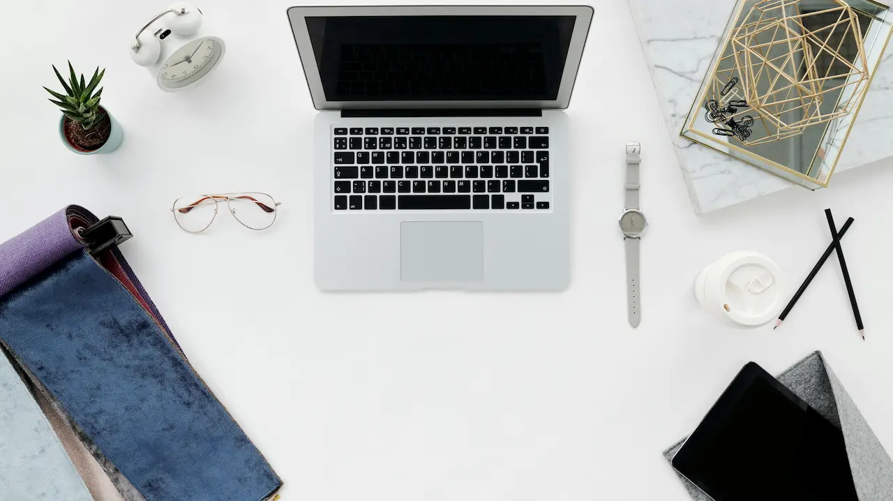a laptop, a piece of fabric, and common interior design tools placed on a table
