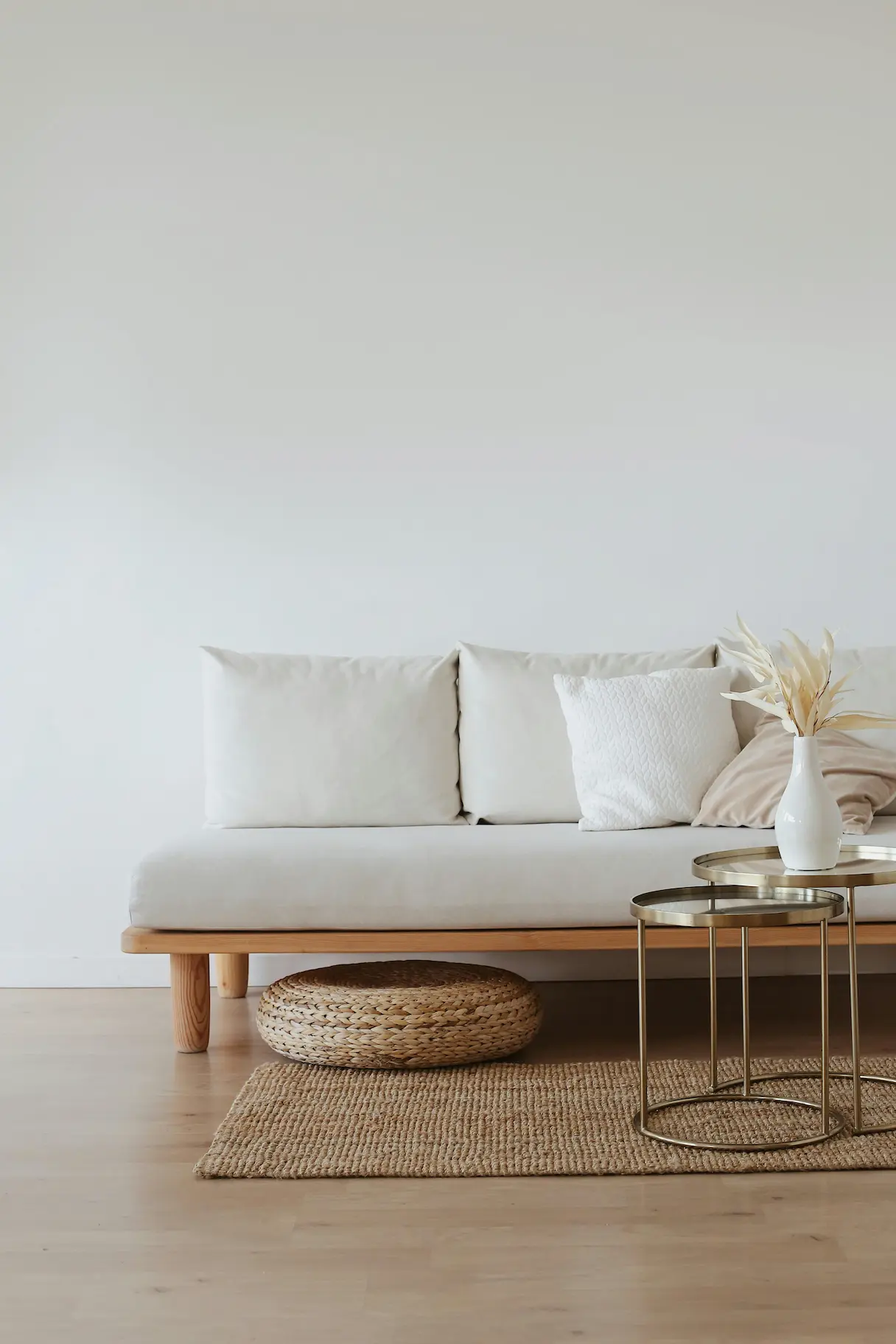 A minimalist living room featuring a white couch on a wooden floor, showcasing clean, simple design.