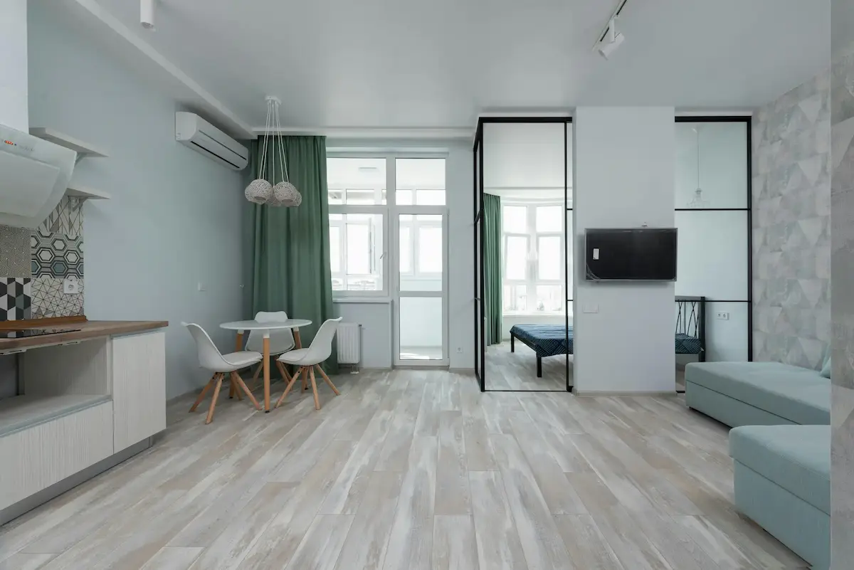 Interior of a modern apartment with a minimalist living room, kitchen, and chic couch, featuring natural, soft colours for a calm, inviting atmosphere.