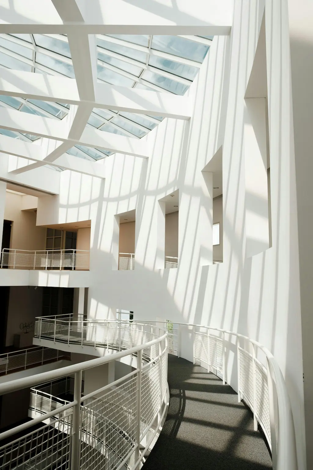 A modern building walkway with a glass ceiling, designed to maximize natural light and create a bright, open space.