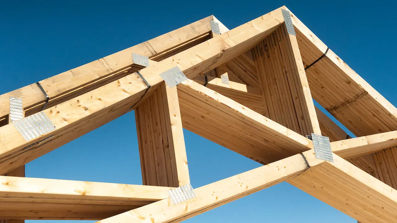 A stack of pre-assembled trusses prepared for installation on a house construction site.