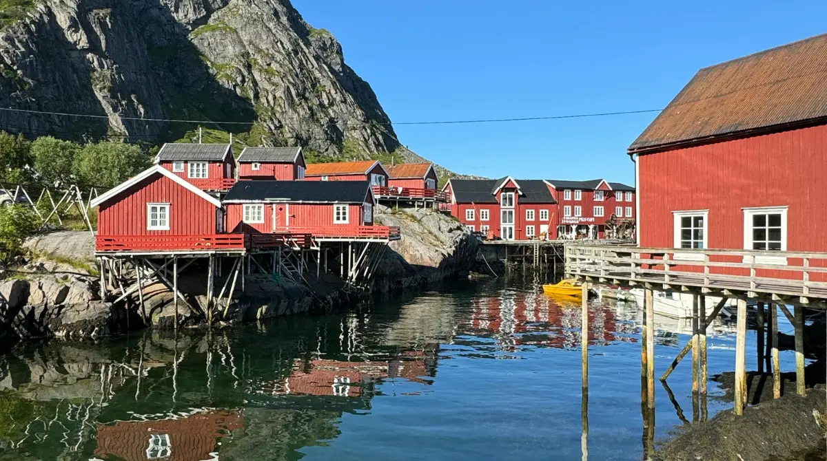 red houses on piers by the water with a hill in the background in Lofoten, Norway