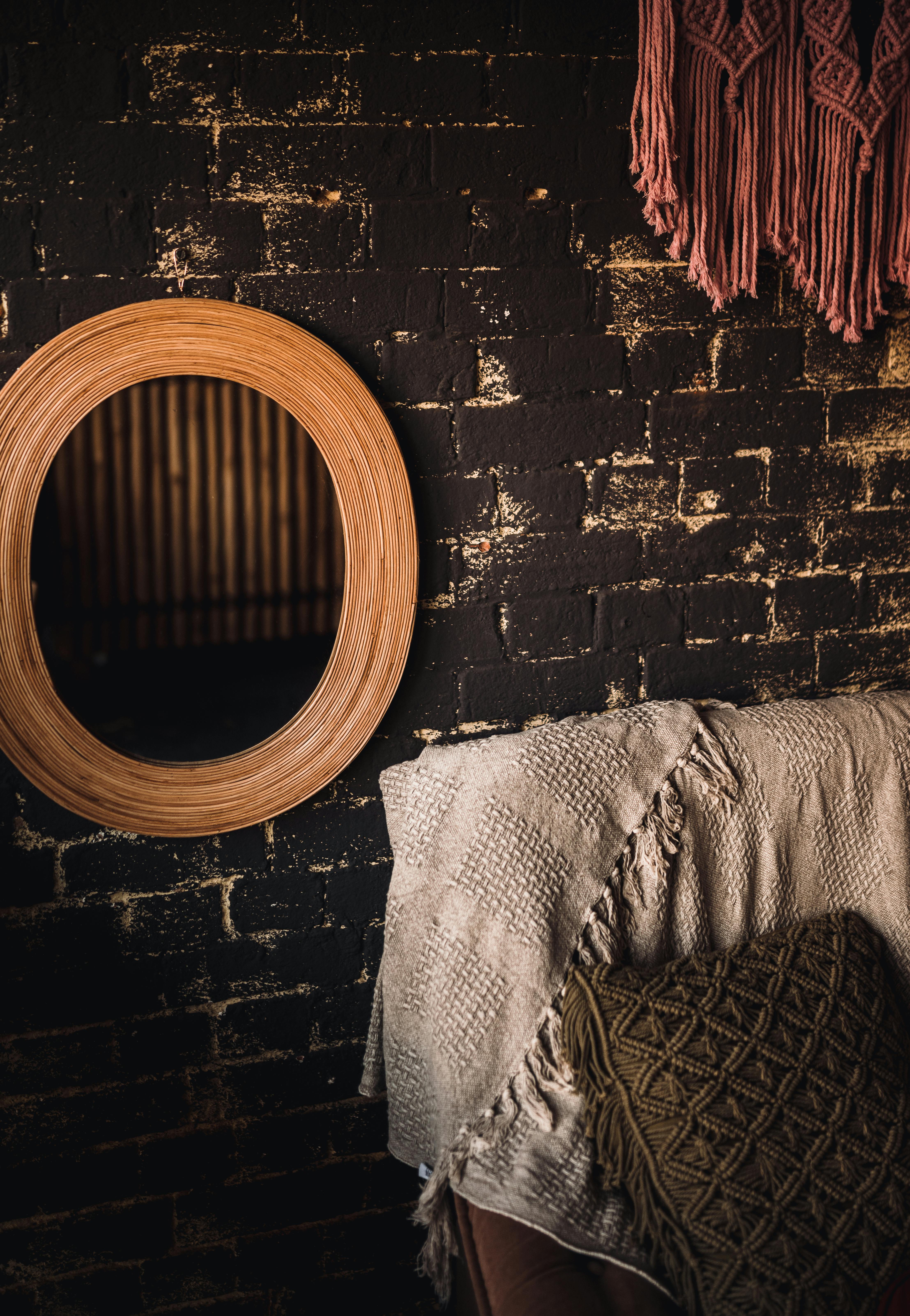 Wooden wall mirror on a brick wall with dark rustic tones.