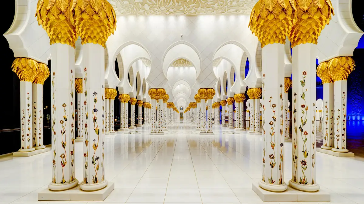 Interior gallery of Sheikh Zayed Mosque, showcasing grand arches, marble columns, and intricate Islamic patterns.