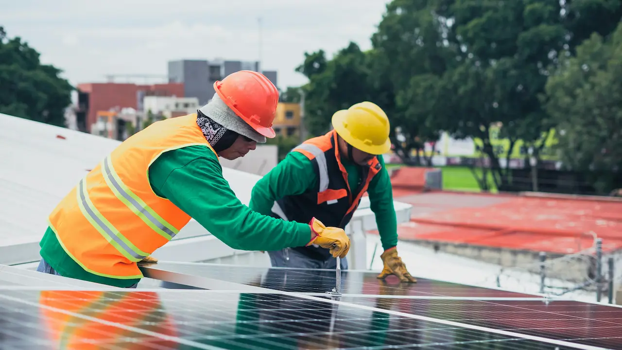 Two workers installing solar panels on a rooftop in New York City.