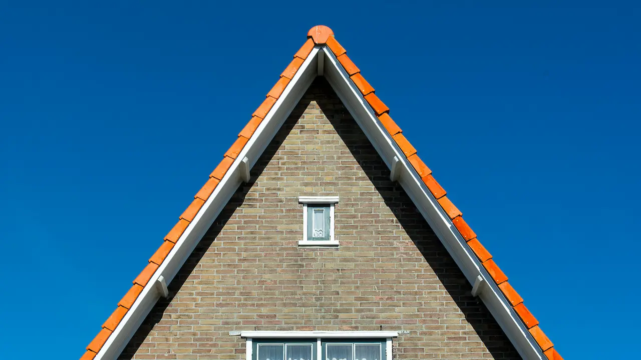 A house with a steep roof and brick exterior, showcasing classic architectural style