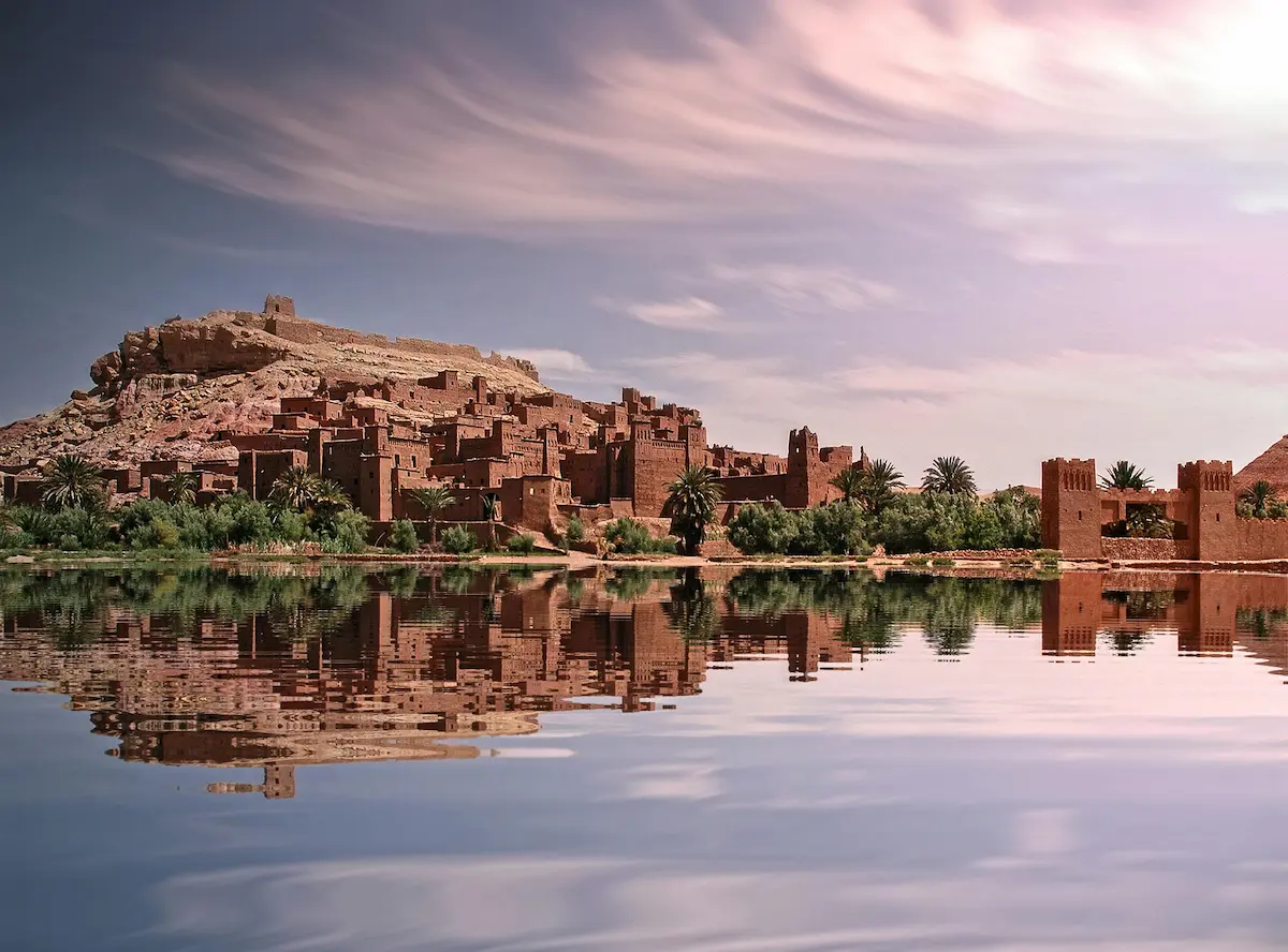 A brown concrete building near a body of water in Ouarzazate, Drâa-Tafilalet, Morocco, constructed with vernacular materials.