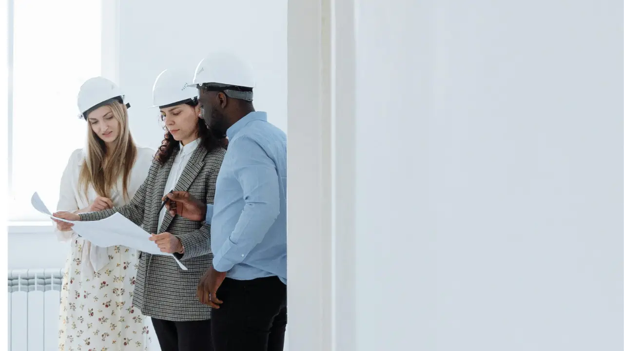 Three architects discussing a residential project while reviewing blueprints.