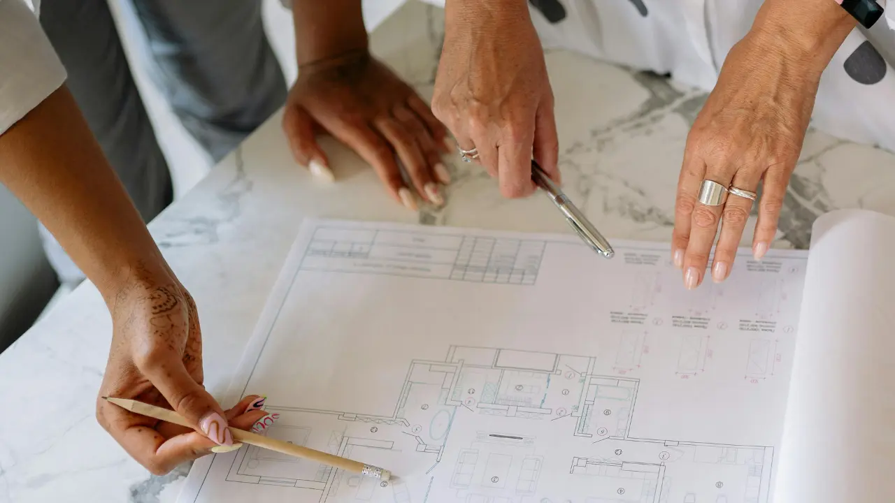 A homeowner, architect, and designer discussing an architectural drawing of a concept house.