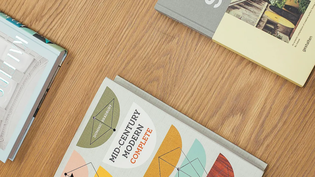 A stack of architecture books resting on a table, showcasing design, construction, and drawing concepts.