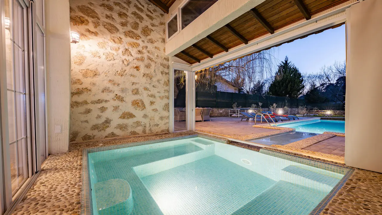 A custom house featuring natural elements like real stone walls, overlooking a pool, blending organic design with luxury.
