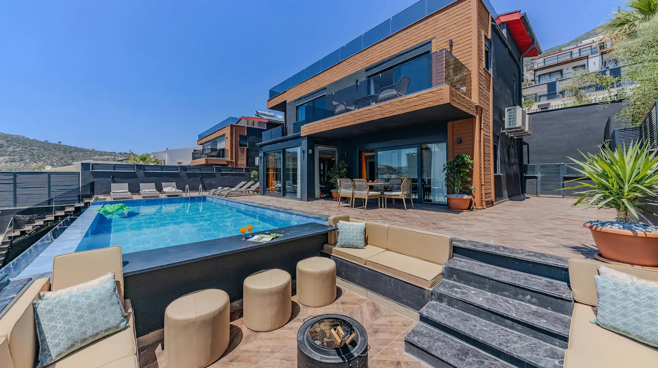 A luxury custom-designed house with a large pool and patio area in front, offering an elegant outdoor living space.