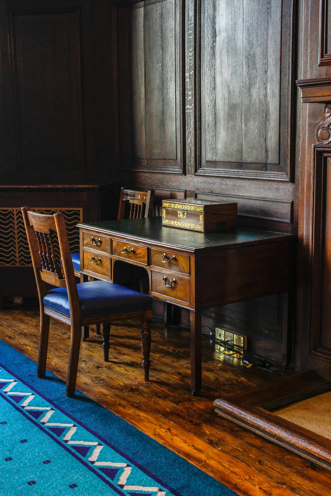 A mahogany pedestal desk with matching chairs in a refined setting, showcasing expert craftsmanship and classic design.
