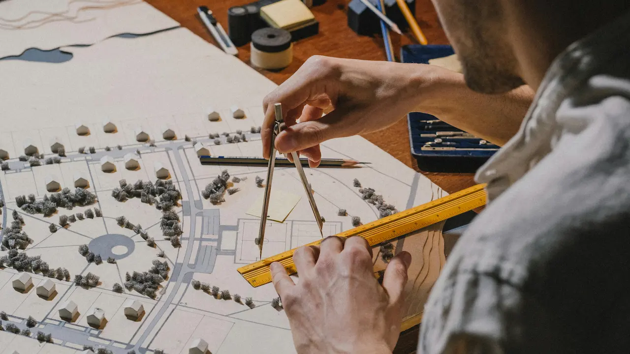 A student working on an architectural model, focused on crafting details and design elements for a project.