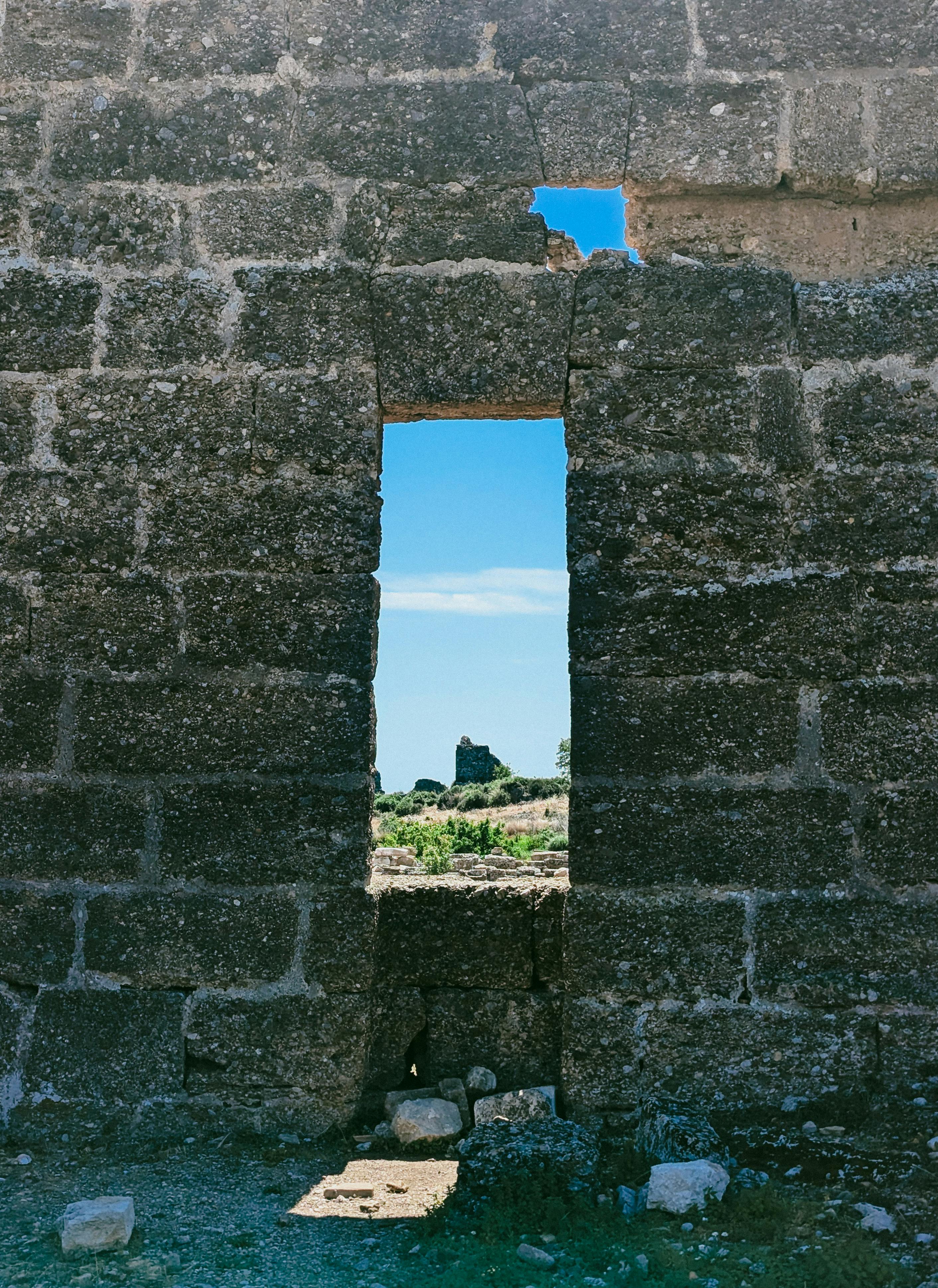 Stone-framed window opening overlooking ancient ruins.