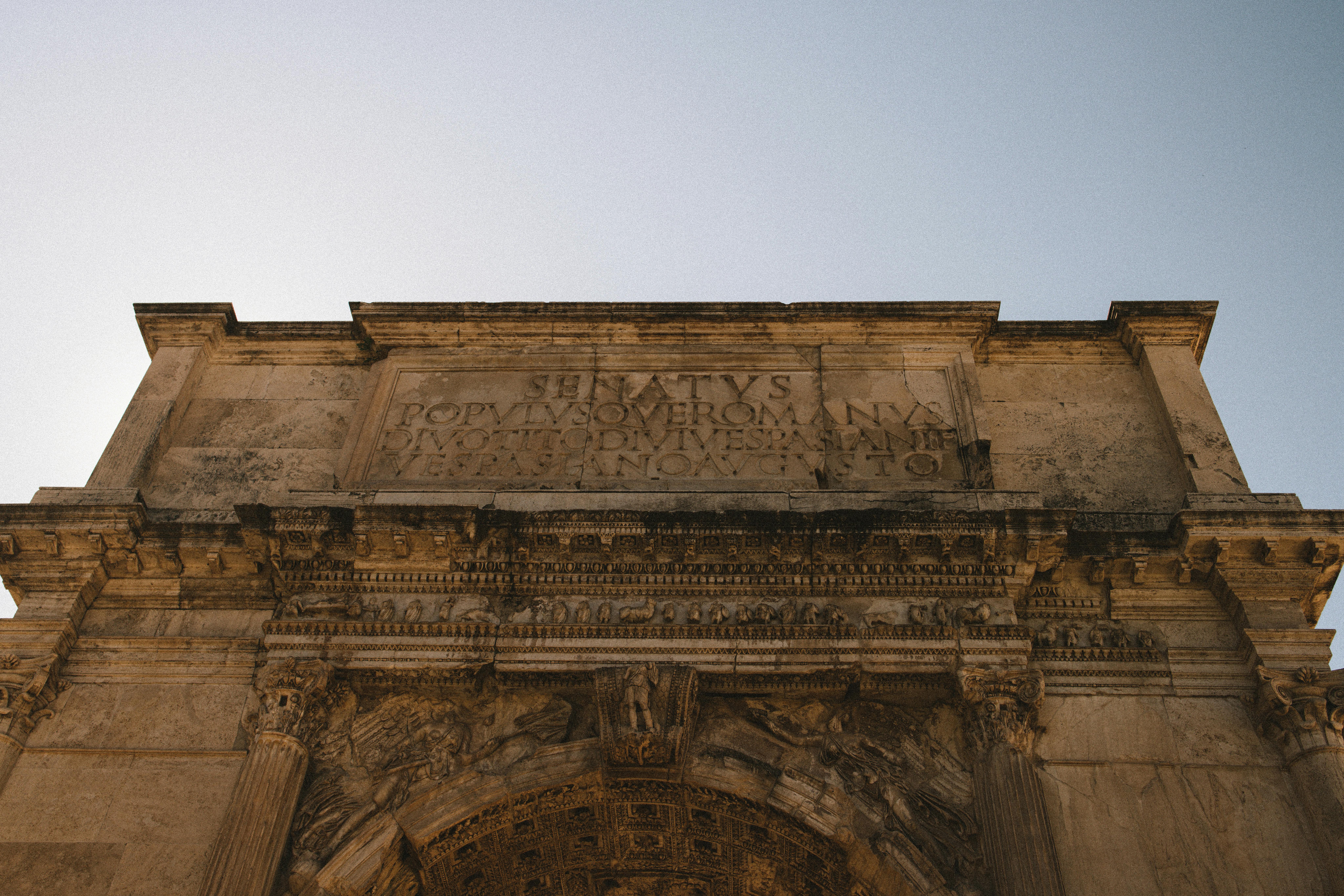 Low angle view of the Arch of Titus in Rome showing carved reliefs and ancient structure.