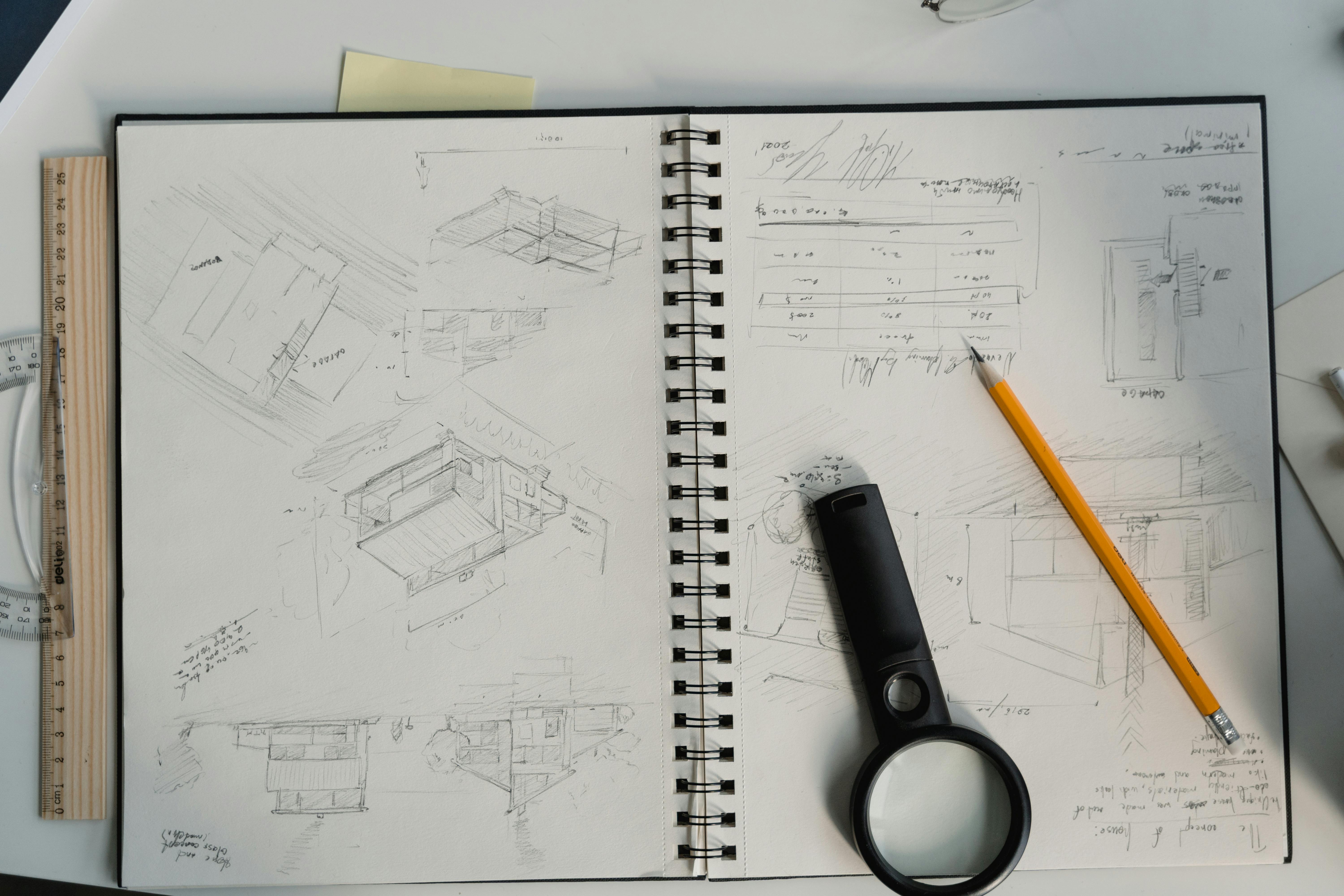 Architect working at a drafting table with hand-drawn concept sketches for a house design.