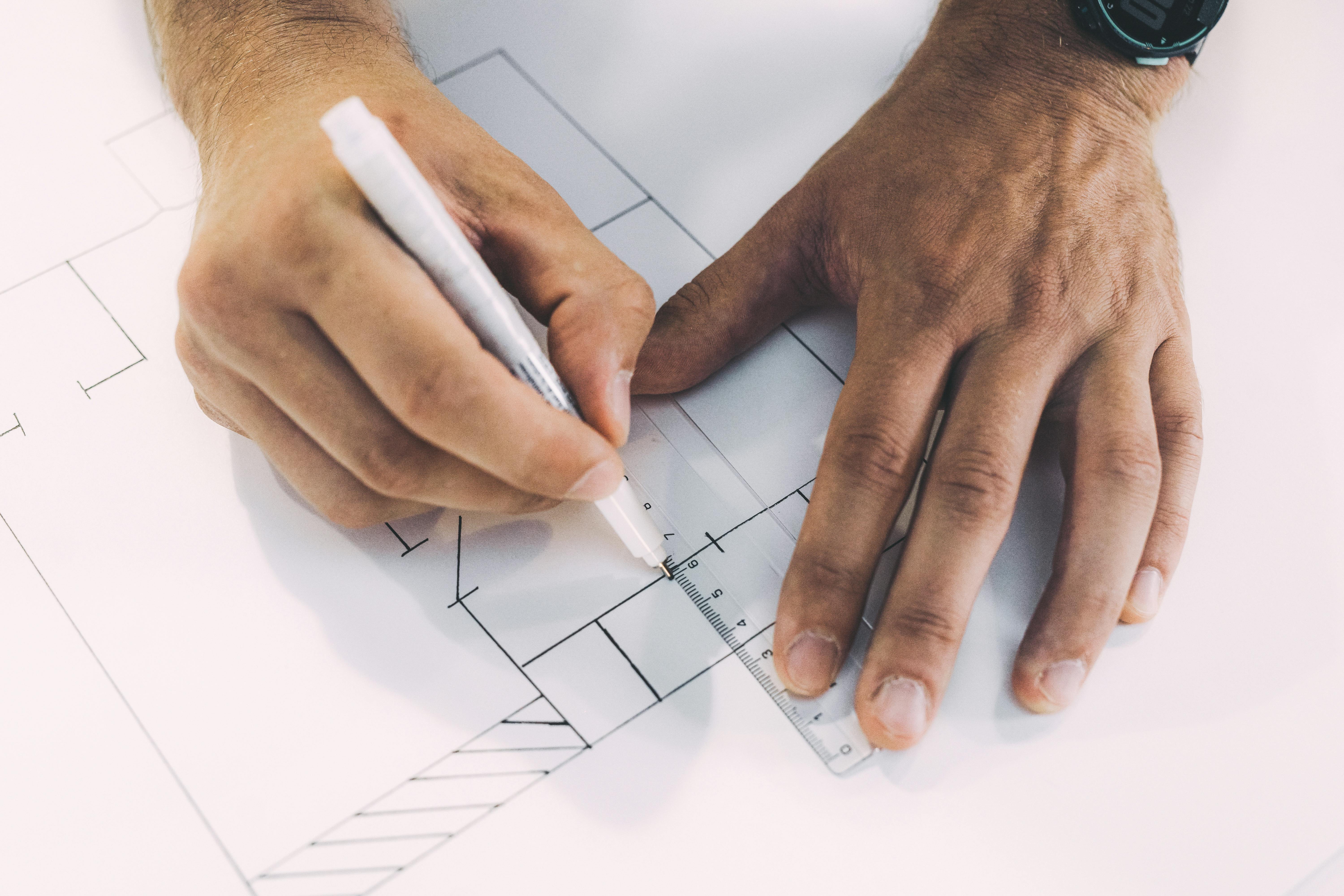 Close-up of an architect manually drawing a blueprint, focusing on precise details and measurements.