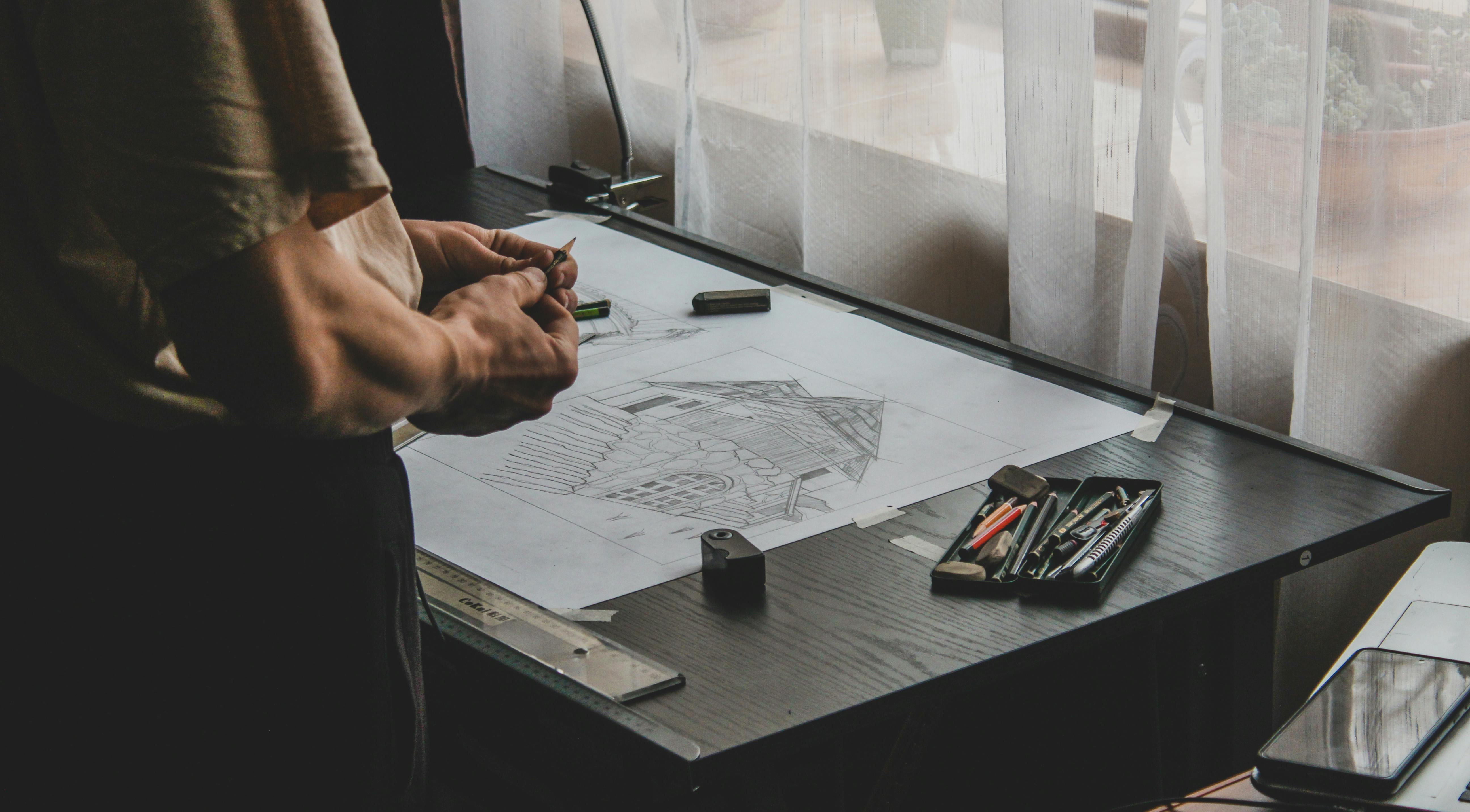 Architect sketching a design on paper, showcasing the early stages of architectural planning.