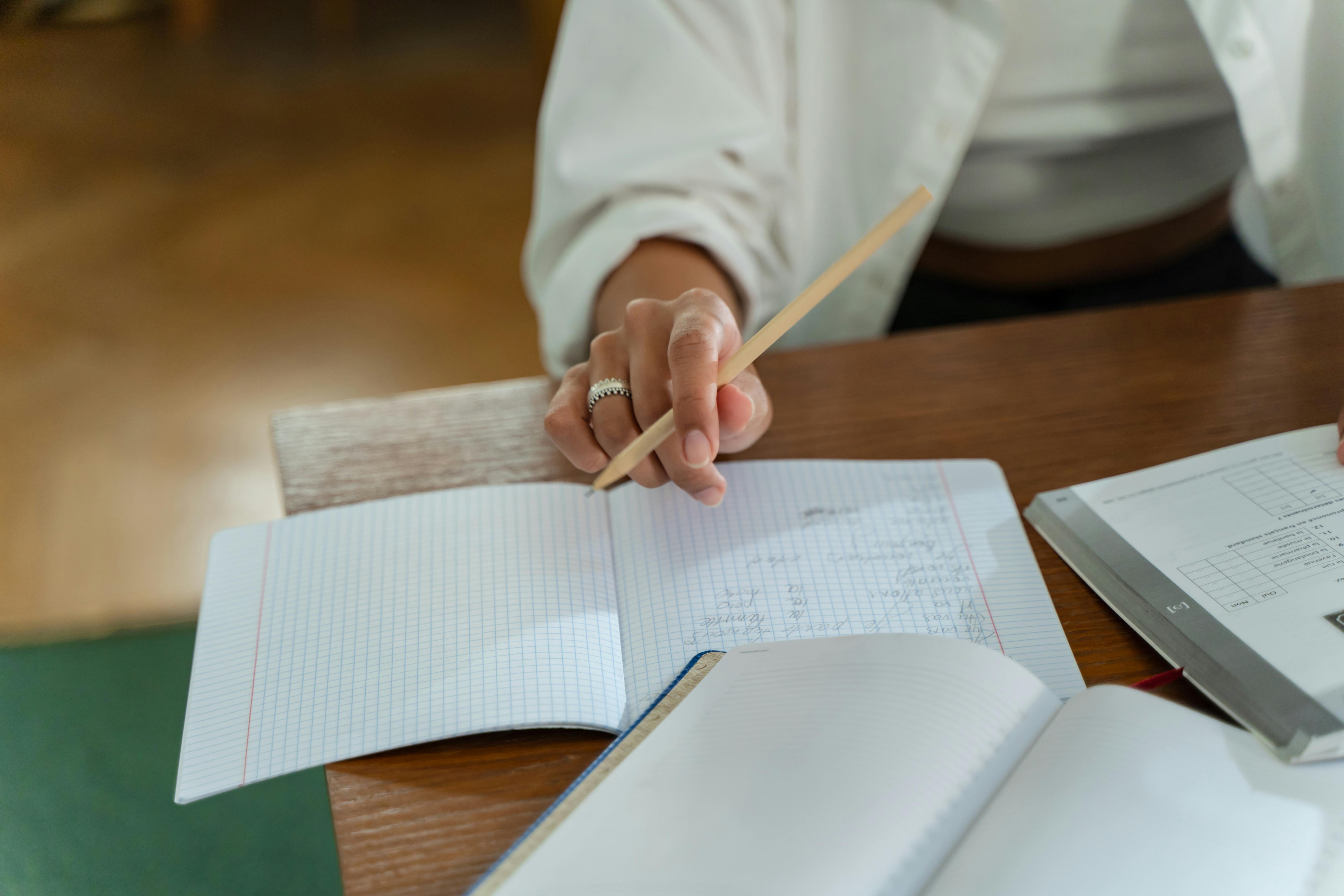 Student sitting on a wooden table, holding a pencil and concentrating on an architecture aptitude exercise.