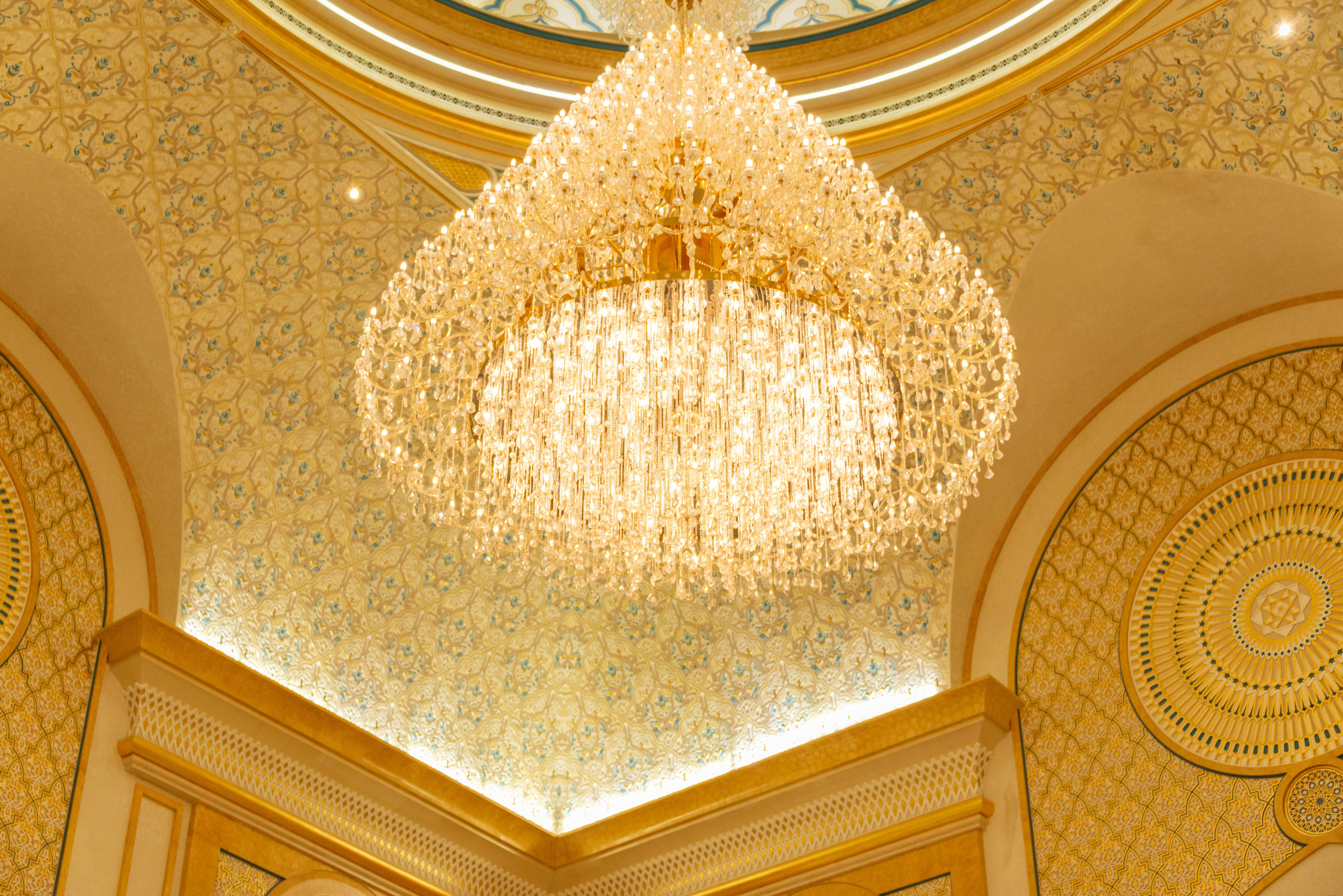 Art Deco chandelier with golden ceiling decor in a luxurious interior space.