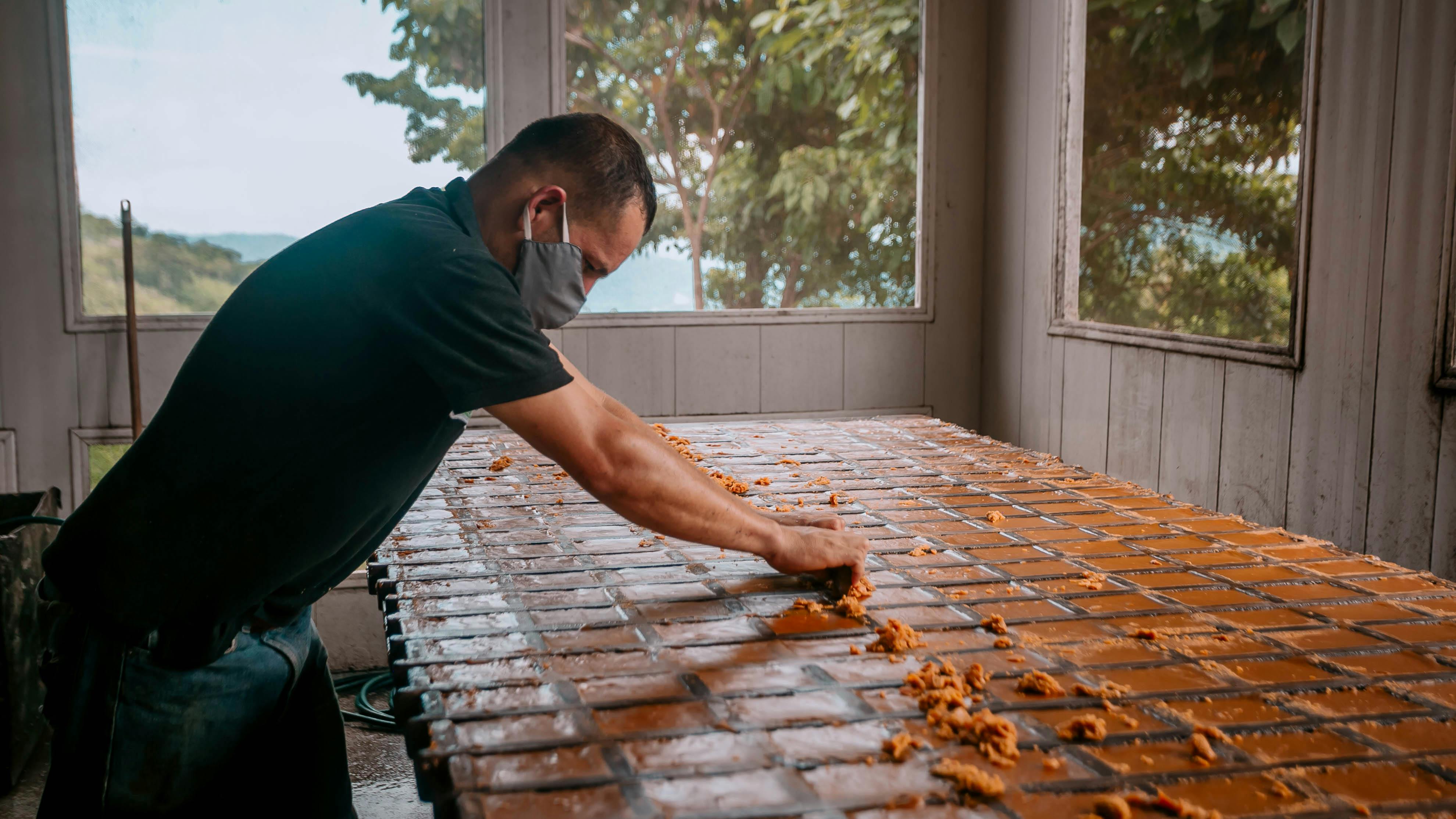 Man shaping bricks in wooden forms during the brickmaking process.
