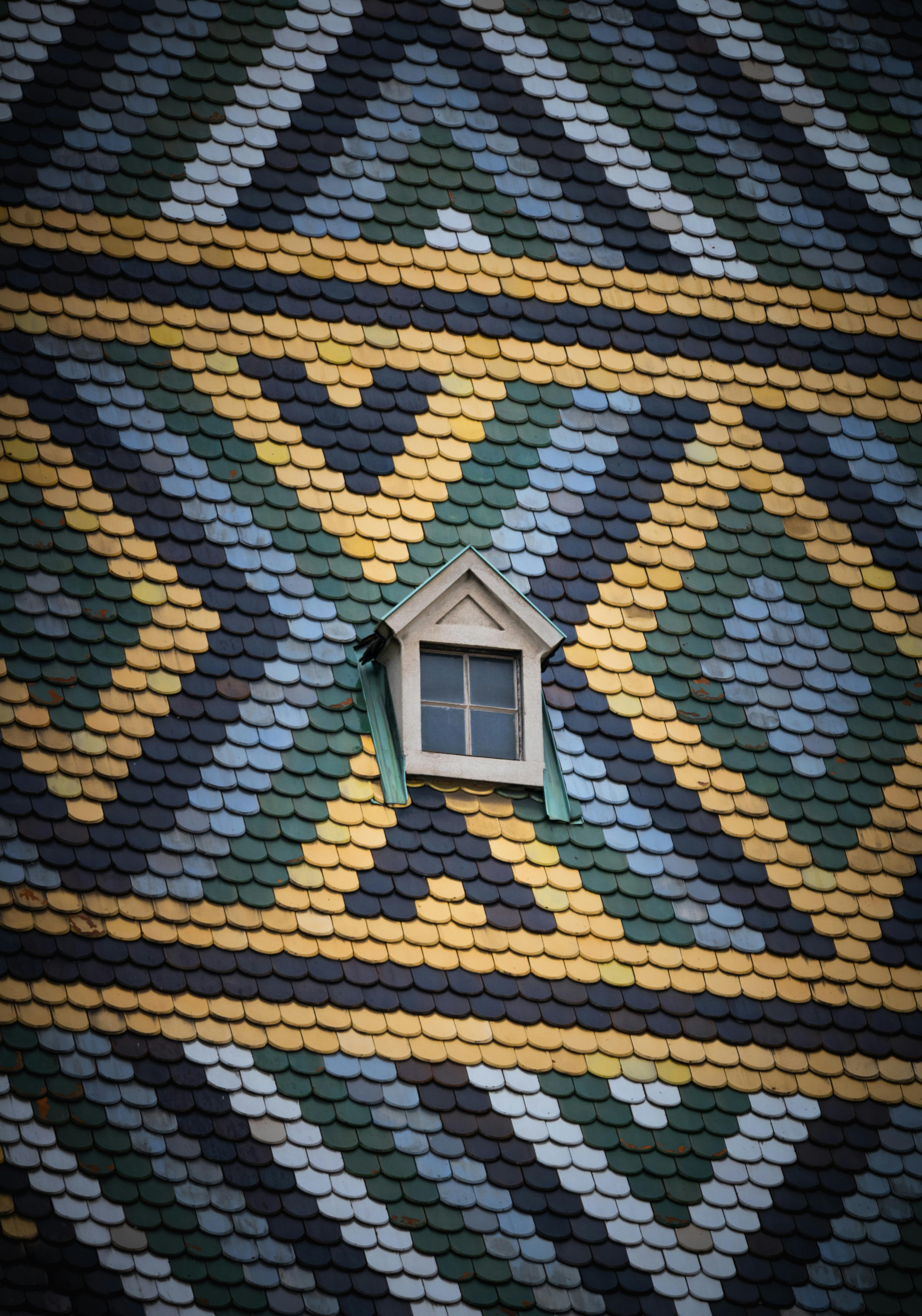 A window framed by a colorful tile roof, showcasing a blend of medieval and modern architectural styles in Vienna, Austria.