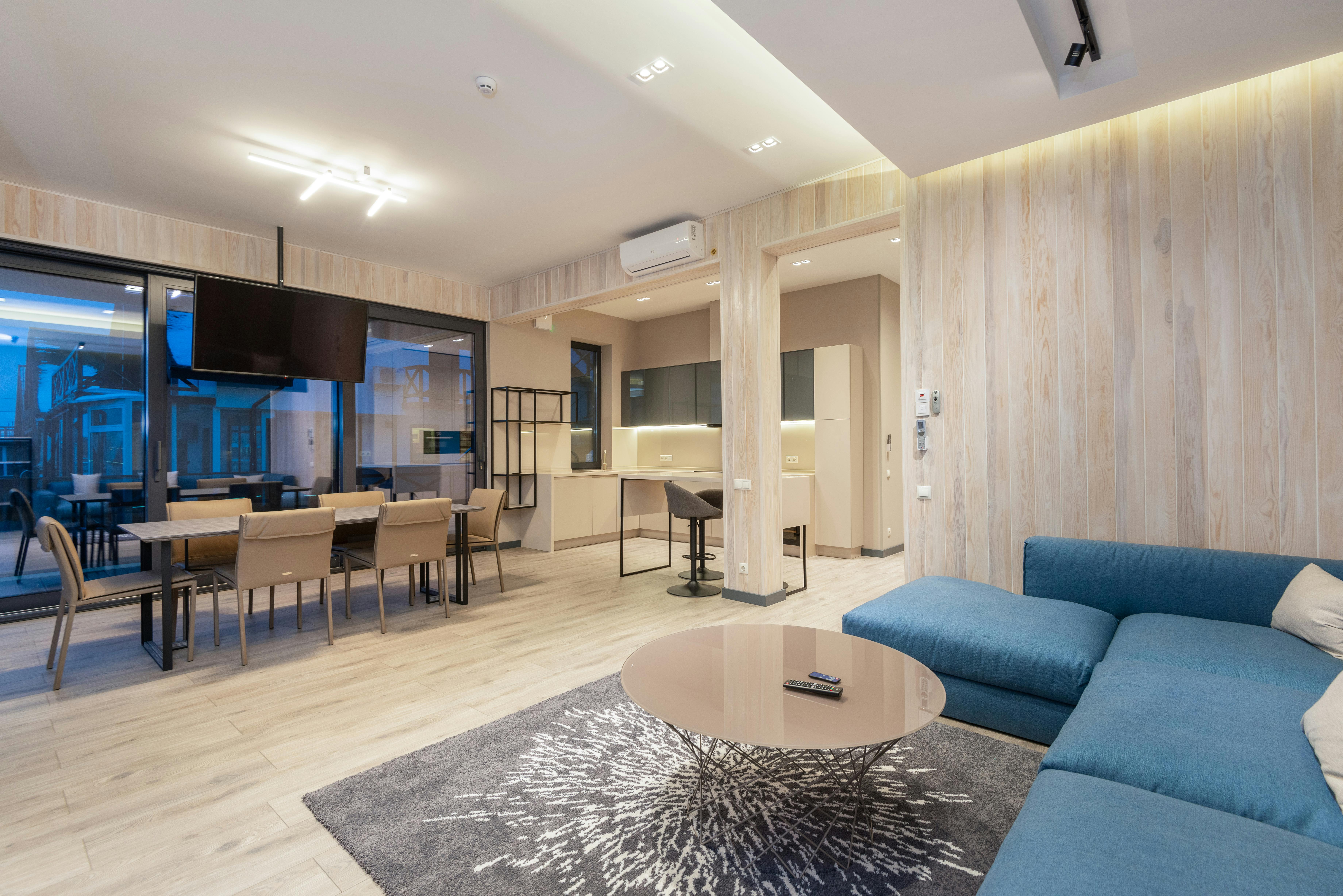 Contemporary studio apartment with a cozy sofa and a compact kitchen, featuring an open-plan layout.
