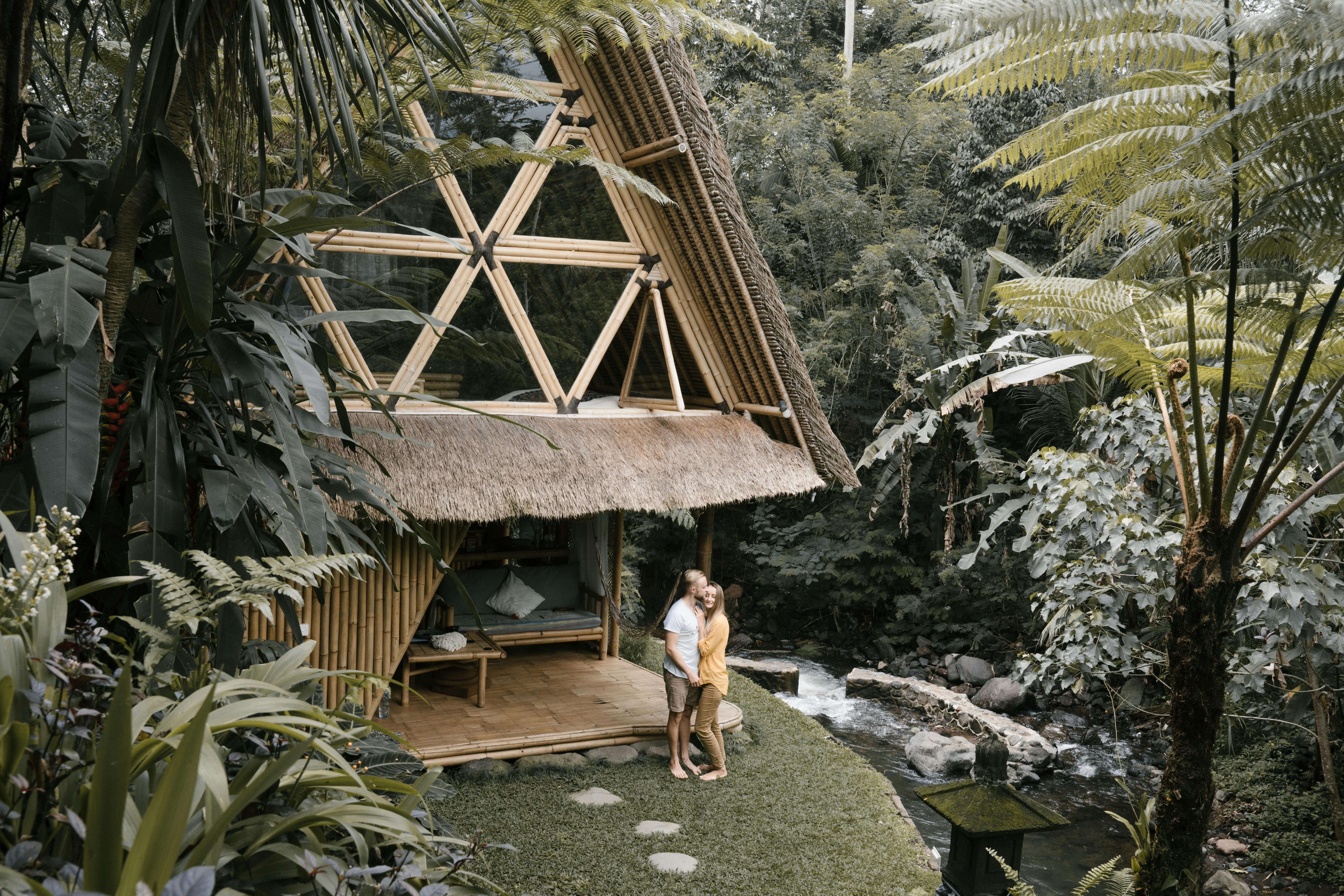 Couple standing in the garden near their mud and bamboo hut in the countryside.