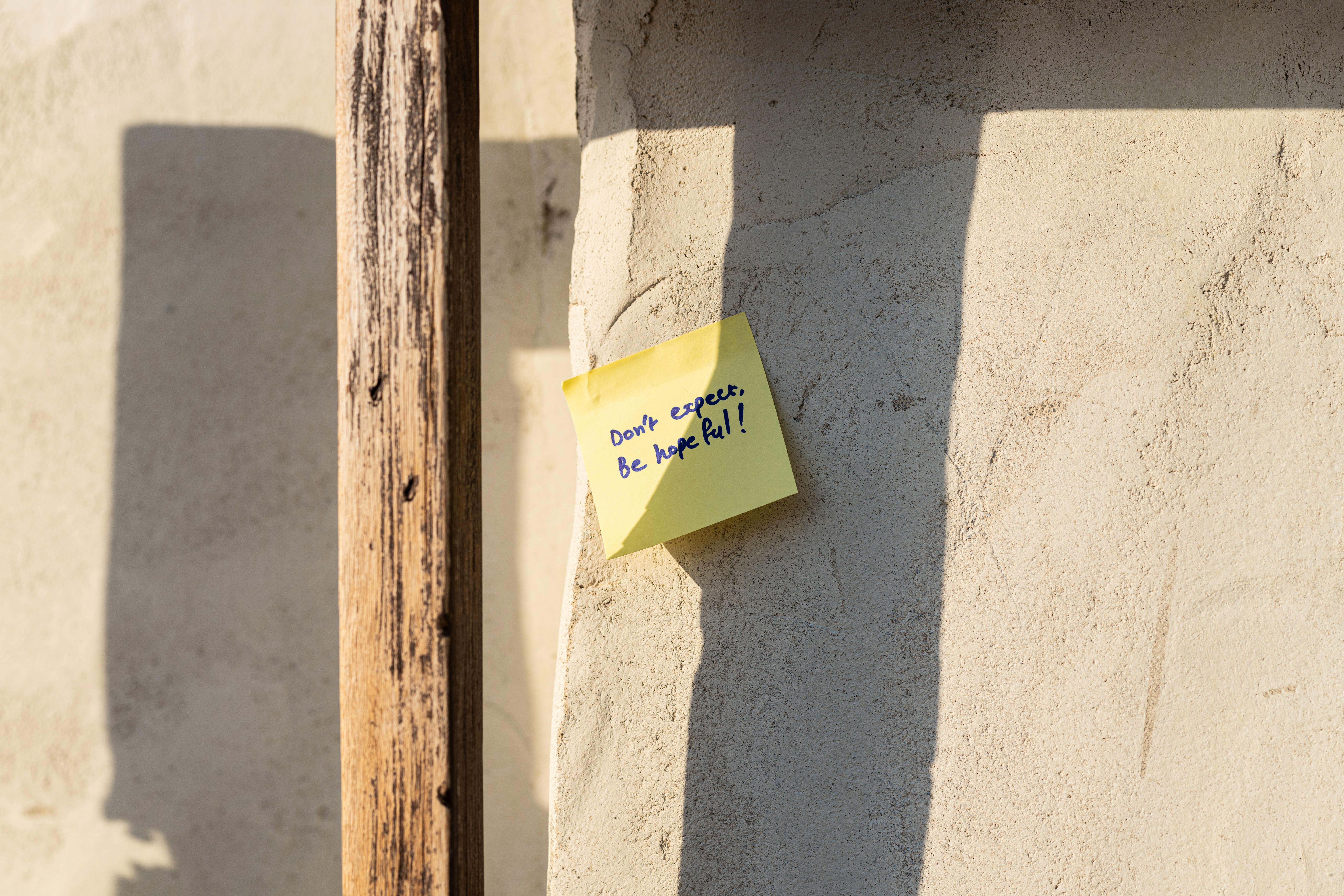 Sticky note with message of hope on sunlit mud wall in traditional Dubai architecture.