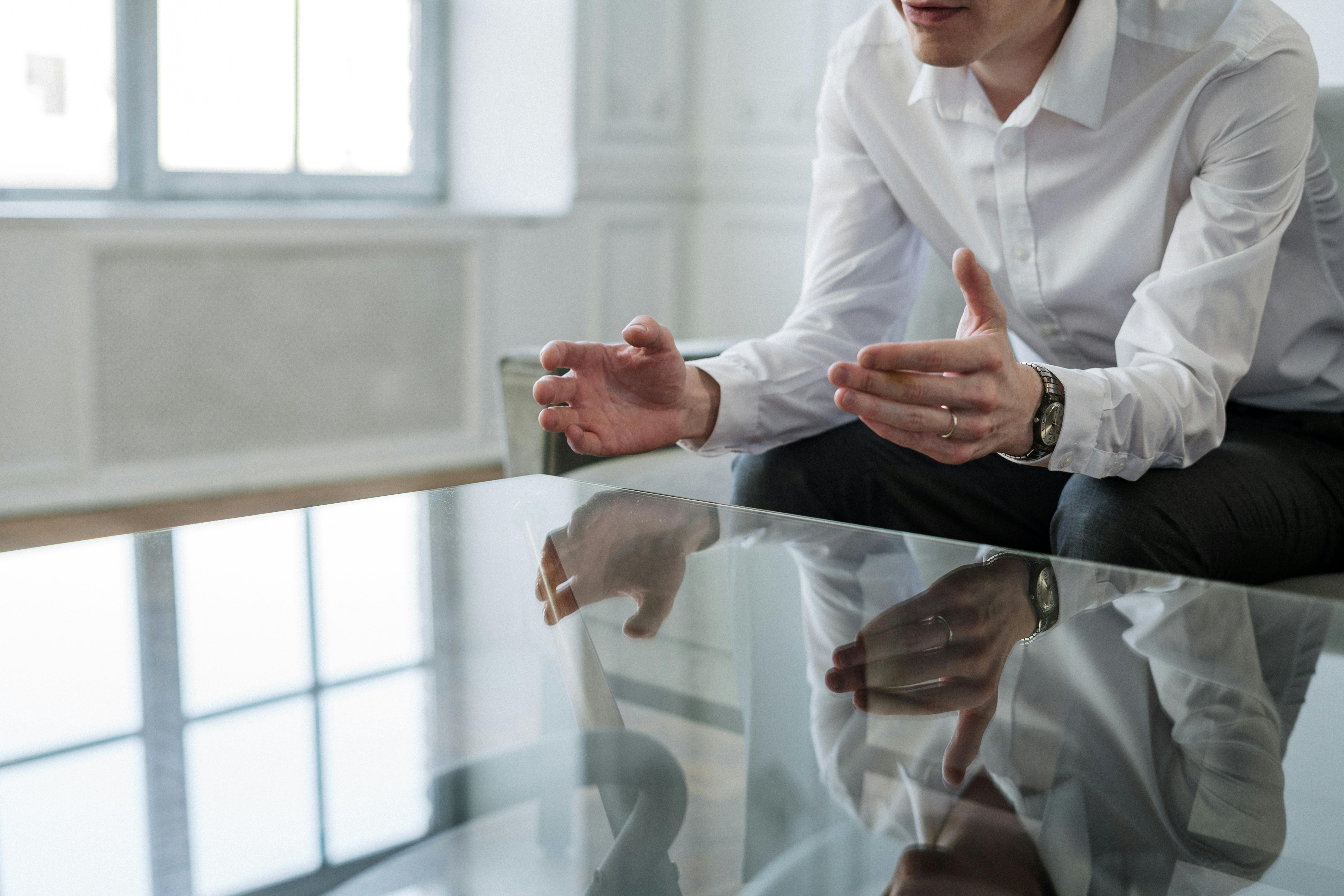 Man in white dress shirt holding another person’s hand with a blank, emotionless expression.