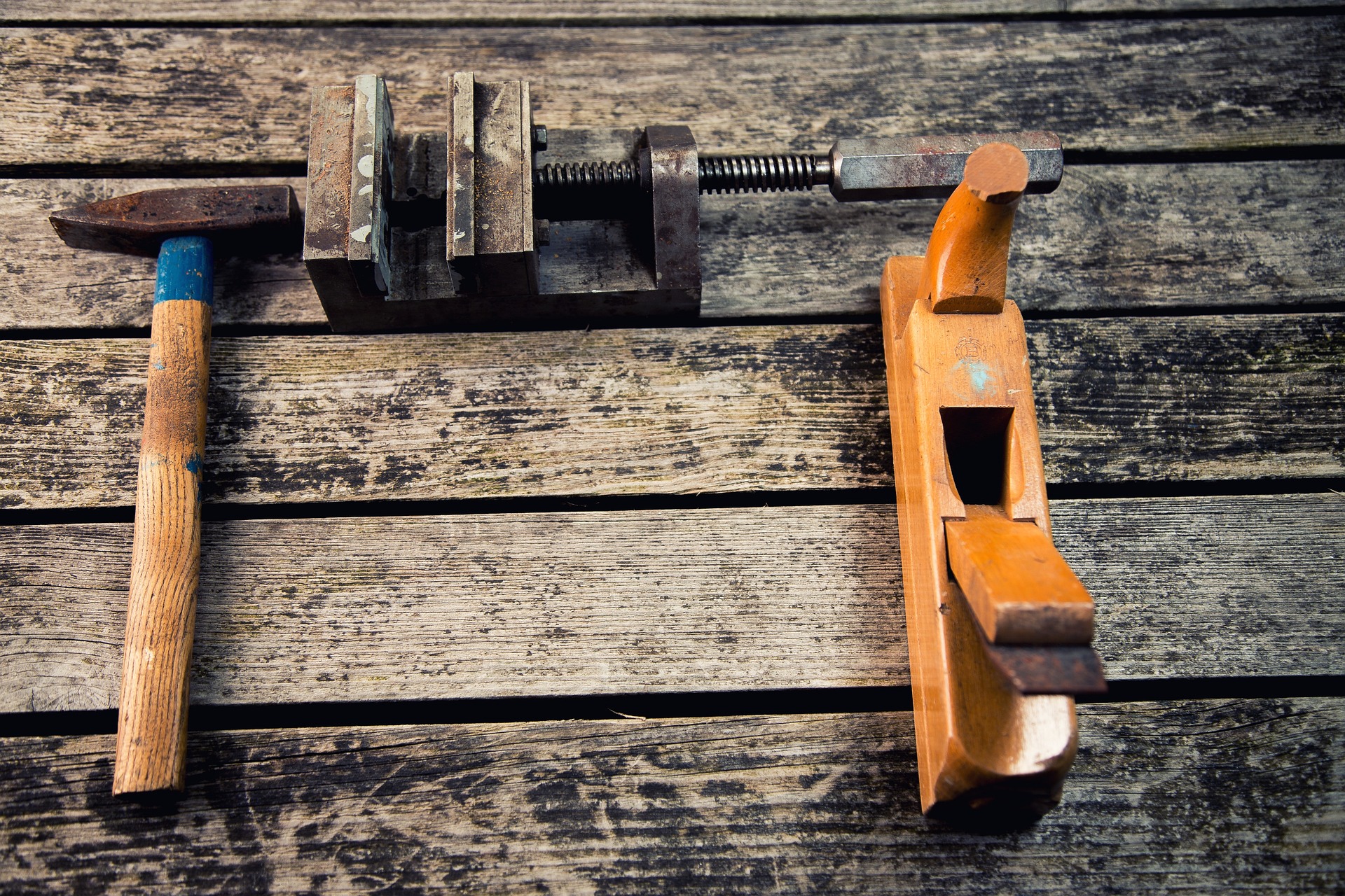 A carpenter's hammer and tools neatly arranged on a wooden workspace.