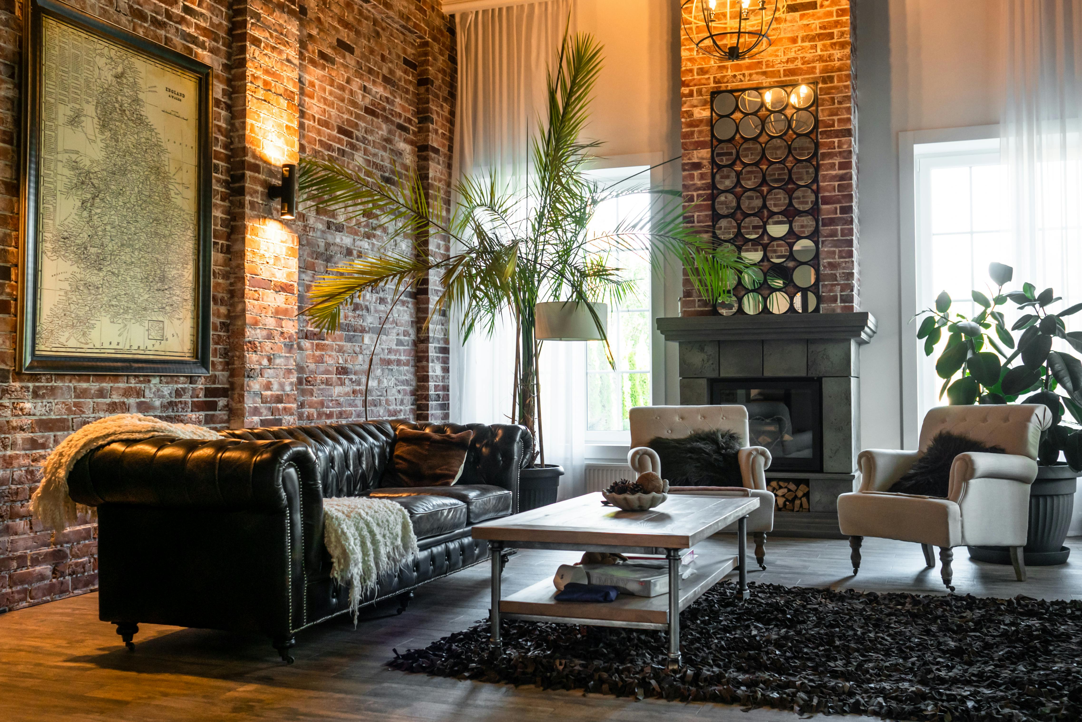 Industrial loft living room with exposed brick walls, large windows, and a mix of modern and vintage furniture.​