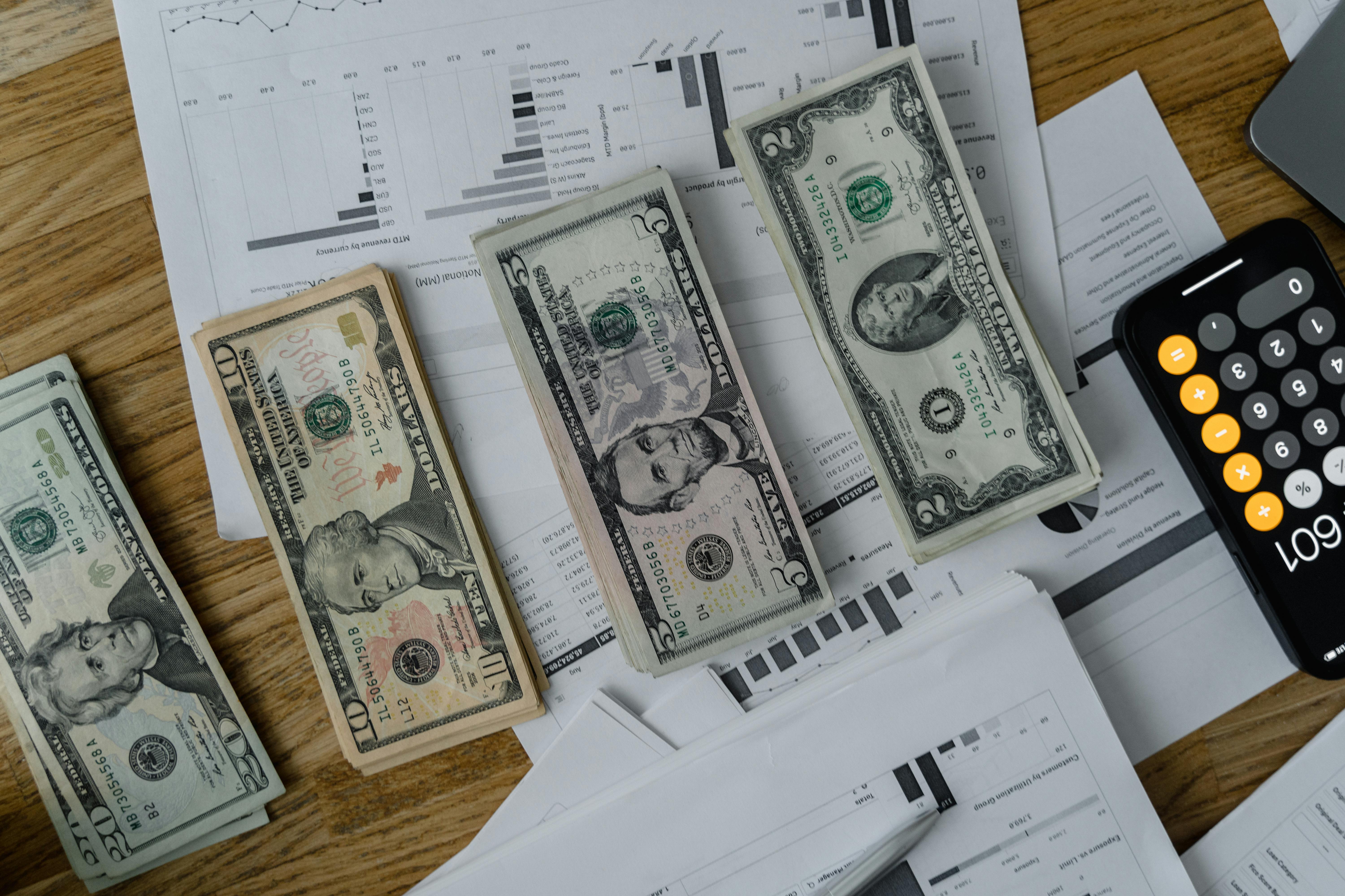 US dollars and a calculator on a table, representing salary comparison between IT and architecture.