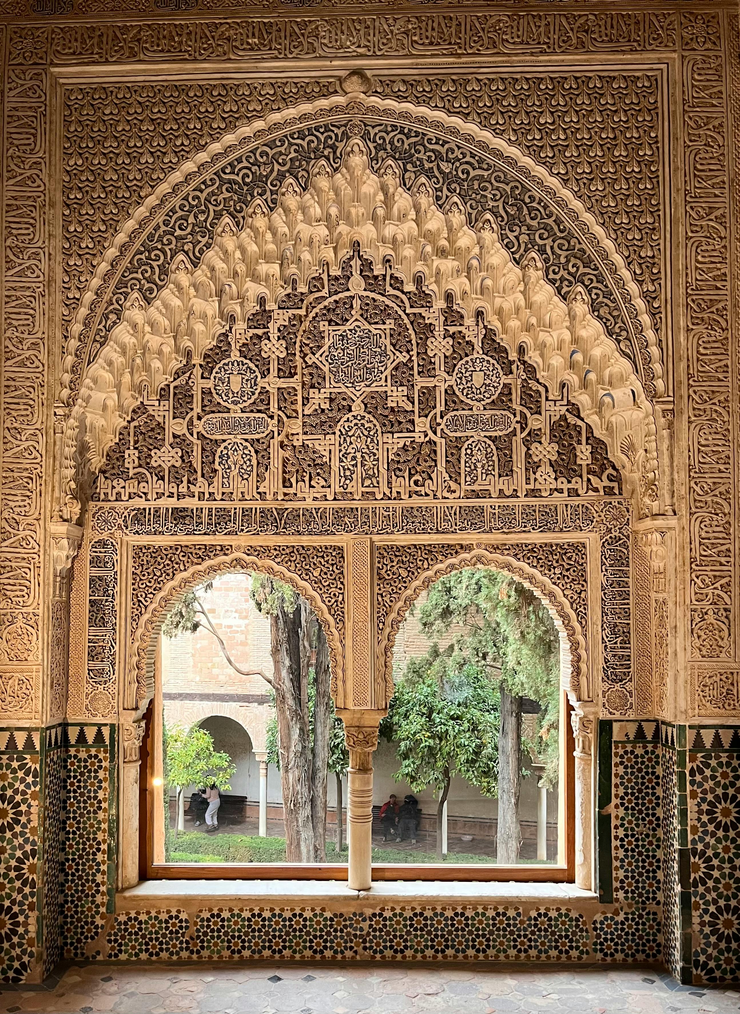 Intricate Moorish mosaic on an interior wall in Granada, Spain, featuring detailed geometric and floral patterns from medieval Islamic architecture.