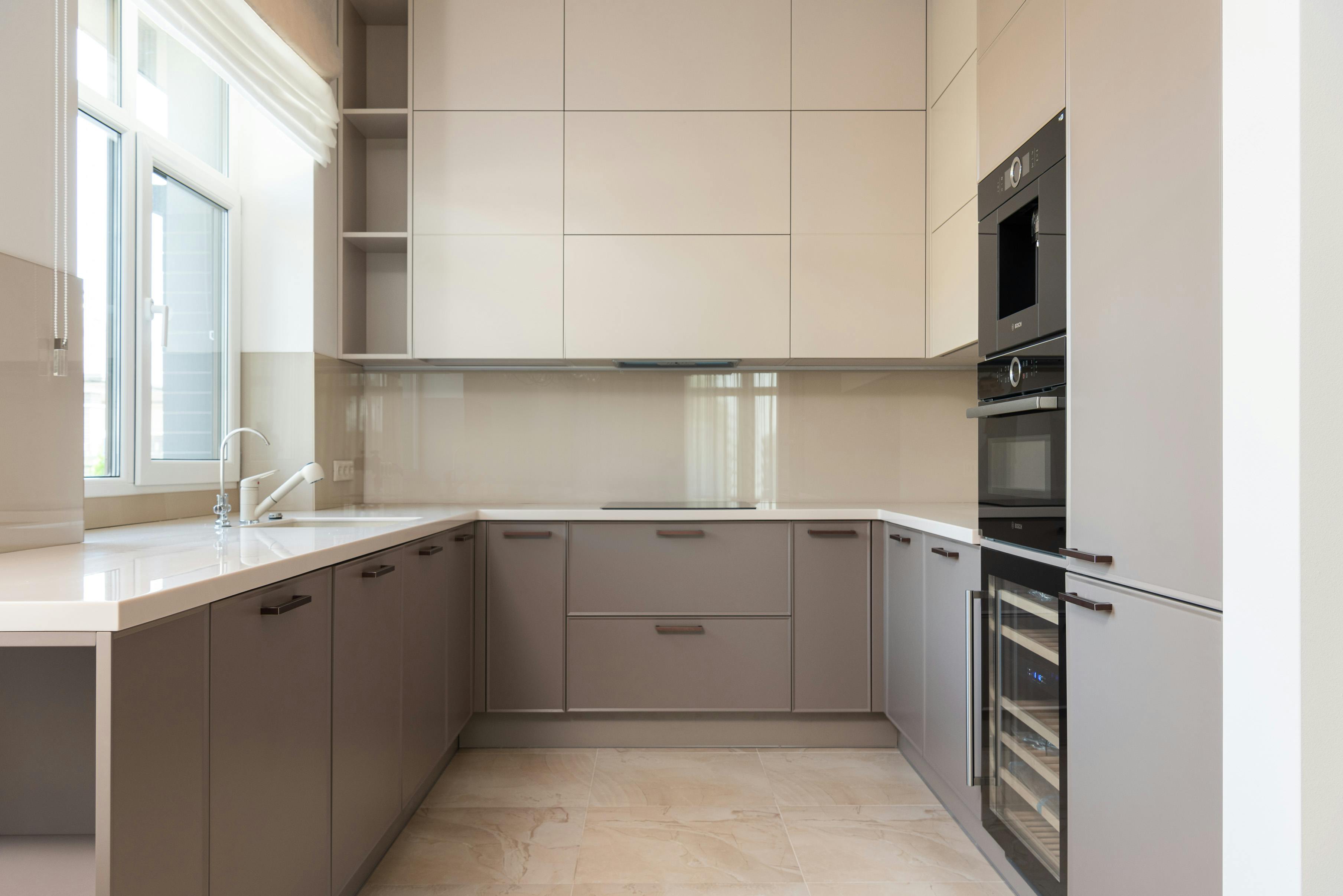 Modern minimalist kitchen with glossy cream cabinets and sleek finishes.